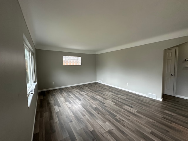 spare room with baseboards, visible vents, and dark wood finished floors