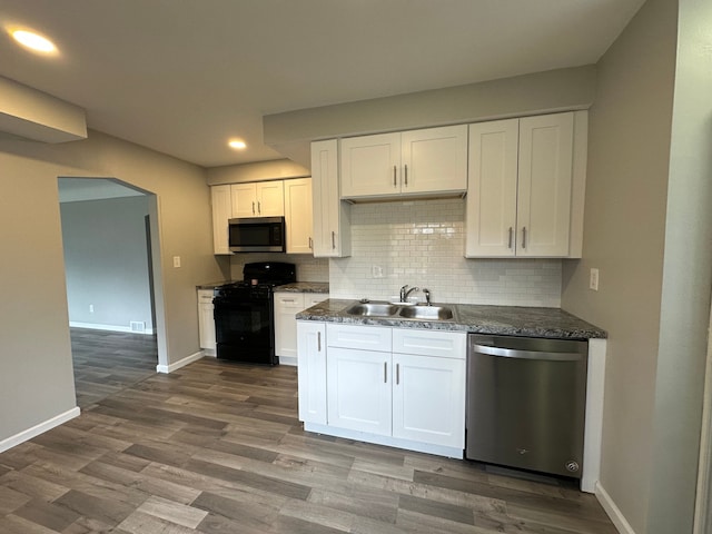 kitchen with baseboards, a sink, appliances with stainless steel finishes, and dark countertops