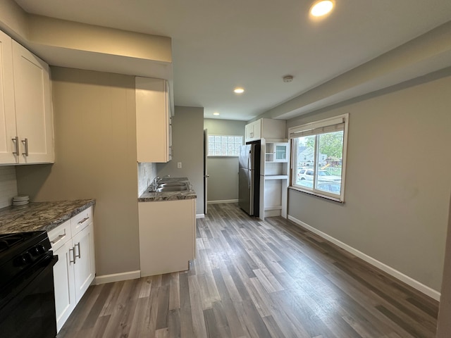 kitchen with white cabinets, a sink, black range with gas stovetop, baseboards, and dark wood-style floors