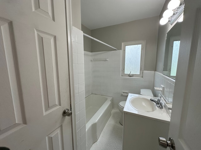 bathroom featuring tile patterned flooring, vanity, toilet, tile walls, and bathtub / shower combination