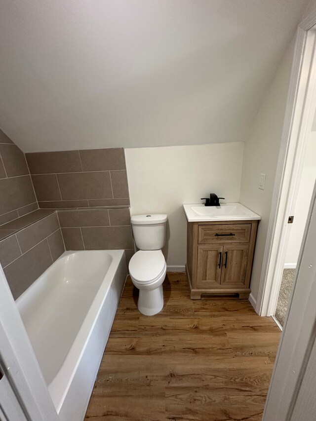 9615 Woodland Ct, Ypsilanti, MI 48197 - bathroom with vanity, a bathing tub, toilet, wood finished floors, and lofted ceiling
