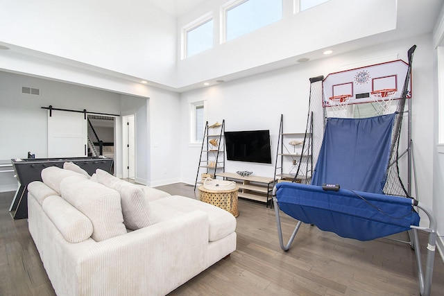living room featuring wood finished floors, a barn door, and visible vents
