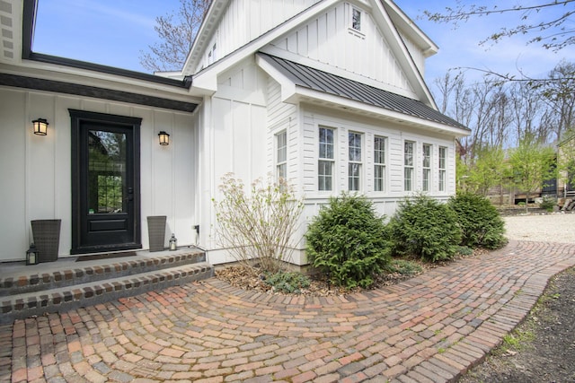 view of exterior entry featuring board and batten siding and metal roof