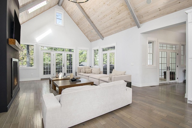 living area with baseboards, high vaulted ceiling, a skylight, and french doors