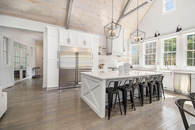 kitchen with an inviting chandelier, a kitchen island, light countertops, white cabinets, and stainless steel appliances