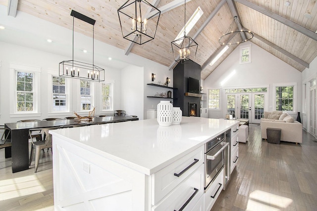 kitchen with an inviting chandelier, stainless steel oven, a center island, wooden ceiling, and french doors