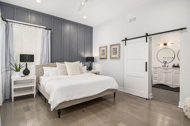 bedroom with visible vents, a barn door, dark wood-type flooring, and recessed lighting