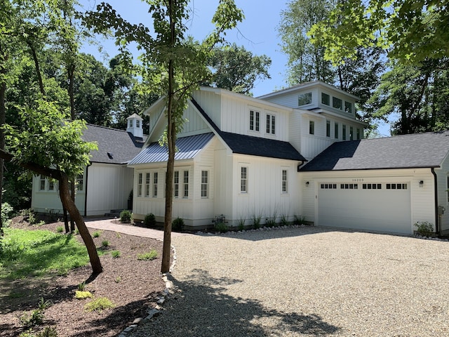 modern farmhouse style home with board and batten siding, an attached garage, roof with shingles, and gravel driveway