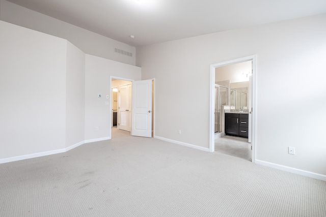 unfurnished bedroom with connected bathroom, light colored carpet, baseboards, and visible vents
