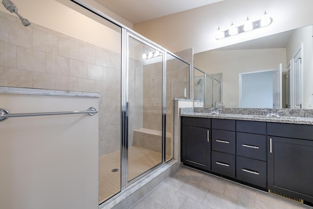 full bath with a sink, tile patterned floors, a shower stall, and double vanity