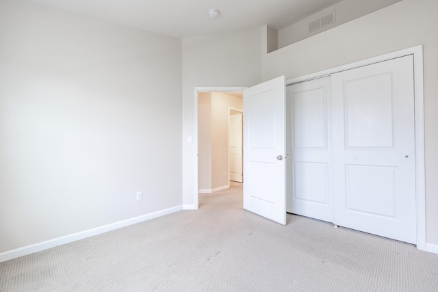unfurnished bedroom with baseboards, light carpet, a closet, and visible vents