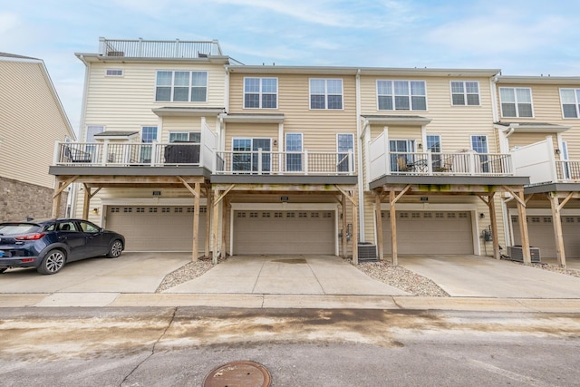 multi unit property featuring an attached garage, driveway, and central AC unit
