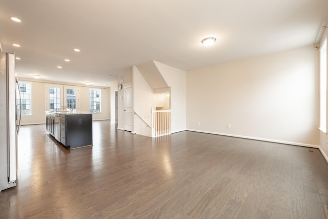 unfurnished living room with recessed lighting, baseboards, dark wood-style floors, and a sink