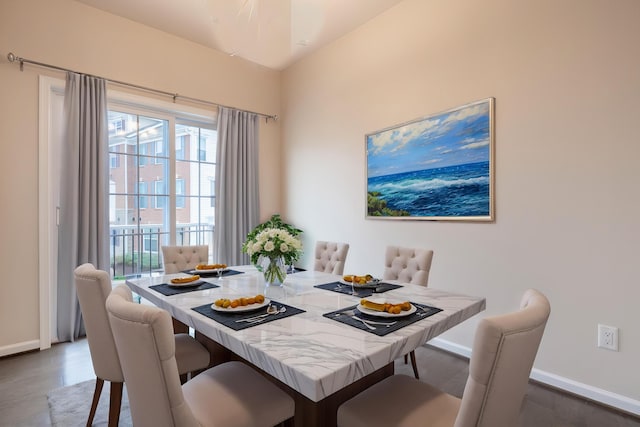 dining space with baseboards, a wealth of natural light, and wood finished floors
