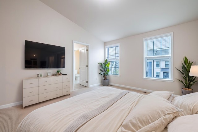 bedroom with baseboards, light colored carpet, ensuite bathroom, and lofted ceiling