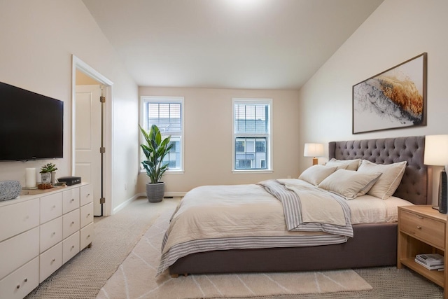 bedroom featuring light colored carpet, baseboards, and vaulted ceiling