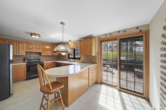 8577 Glenwood Ct, Jackson, MI 49201 - kitchen featuring light countertops, a peninsula, decorative light fixtures, decorative backsplash, and black appliances