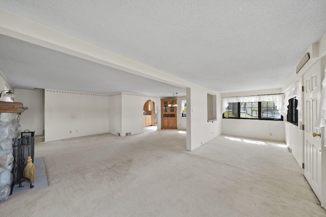 8577 Glenwood Ct, Jackson, MI 49201 - unfurnished living room featuring light colored carpet, arched walkways, a textured ceiling, and a fireplace