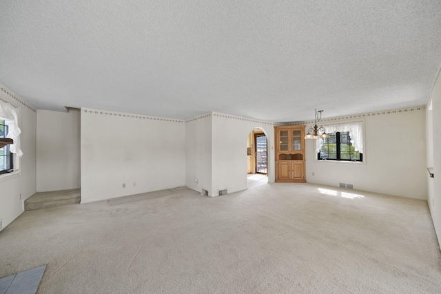 8577 Glenwood Ct, Jackson, MI 49201 - unfurnished living room featuring light colored carpet, a textured ceiling, a chandelier, and visible vents