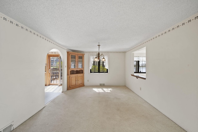 8577 Glenwood Ct, Jackson, MI 49201 - unfurnished dining area with a notable chandelier, arched walkways, a textured ceiling, carpet, and visible vents