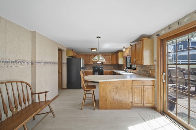 8577 Glenwood Ct, Jackson, MI 49201 - kitchen featuring freestanding refrigerator, a peninsula, a sink, and a wealth of natural light