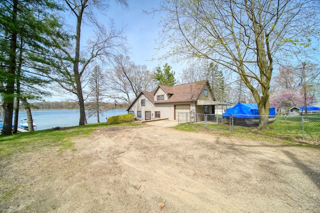 8577 Glenwood Ct, Jackson, MI 49201 - view of property exterior featuring a garage, fence, dirt driveway, and a water view