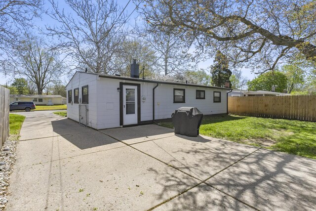 1560 S Carlson St, Westland, MI 48186 - rear view of house with a lawn, a patio, fence, and a chimney