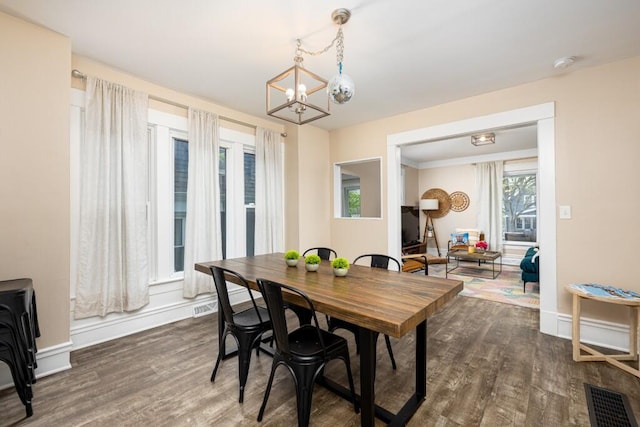 dining space featuring baseboards, visible vents, dark wood-style flooring, and a chandelier
