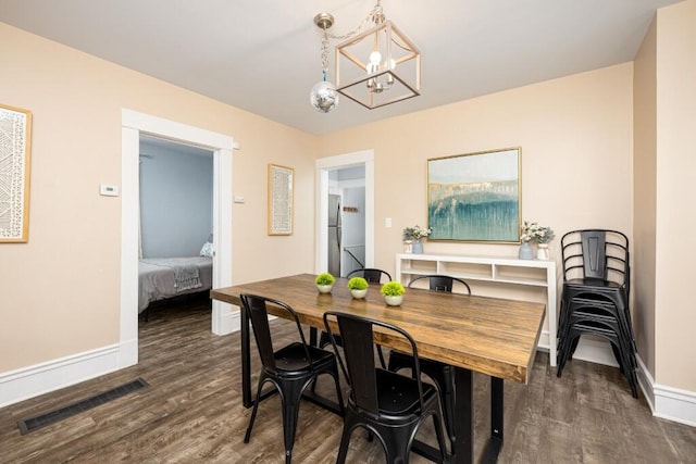 dining space featuring visible vents, baseboards, wood finished floors, and a chandelier