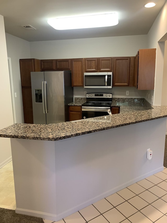 kitchen featuring visible vents, appliances with stainless steel finishes, a peninsula, dark stone counters, and recessed lighting