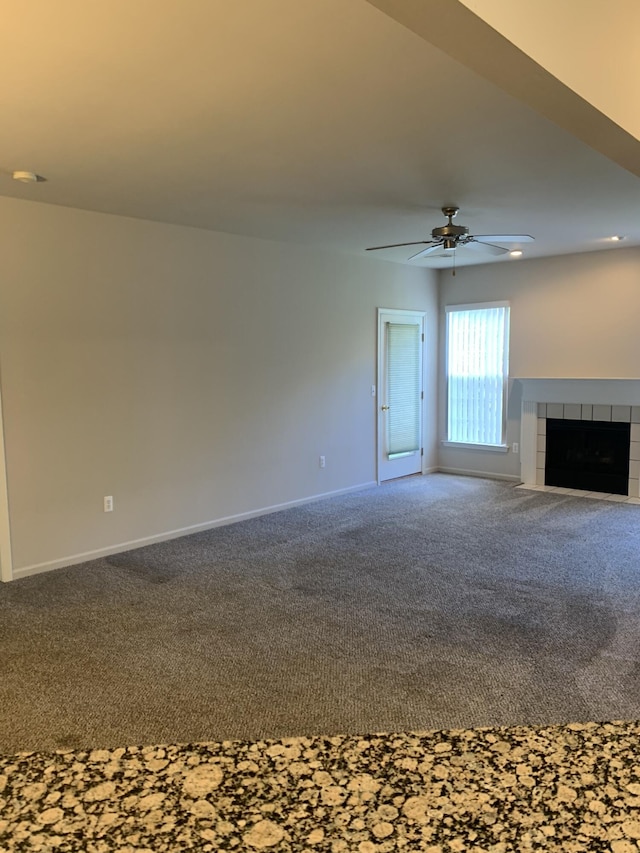 unfurnished living room with baseboards, a ceiling fan, carpet, and a tile fireplace