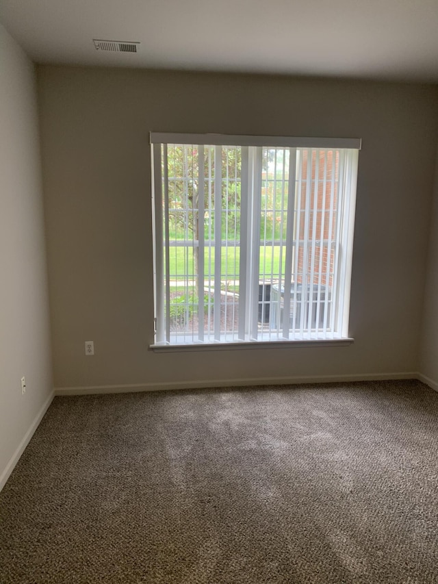 carpeted empty room featuring baseboards and visible vents