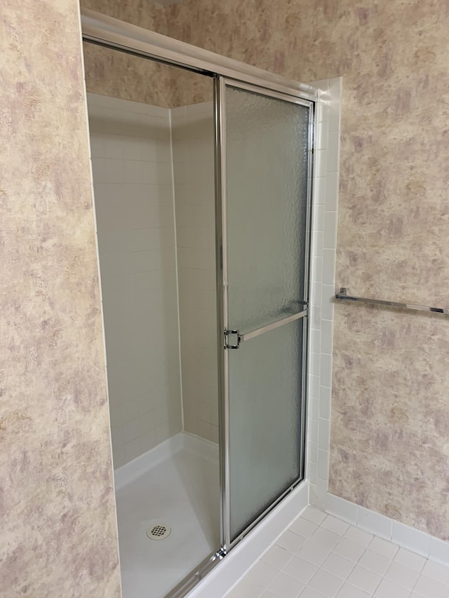bathroom featuring baseboards, tile patterned flooring, and a shower with shower door