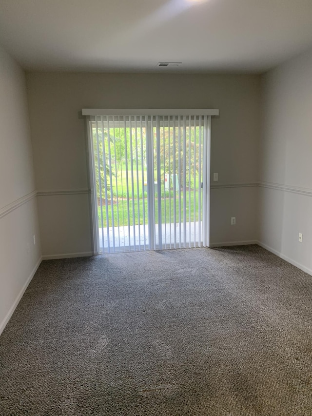 carpeted spare room featuring baseboards and visible vents