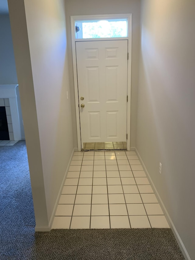 entryway featuring light carpet, light tile patterned floors, and a tile fireplace