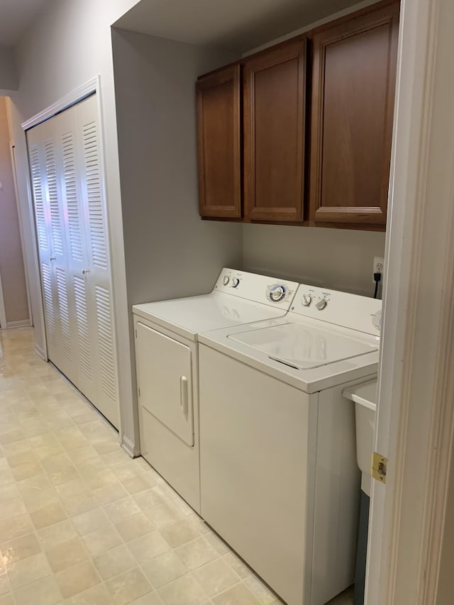 laundry area featuring independent washer and dryer, baseboards, light floors, and cabinet space