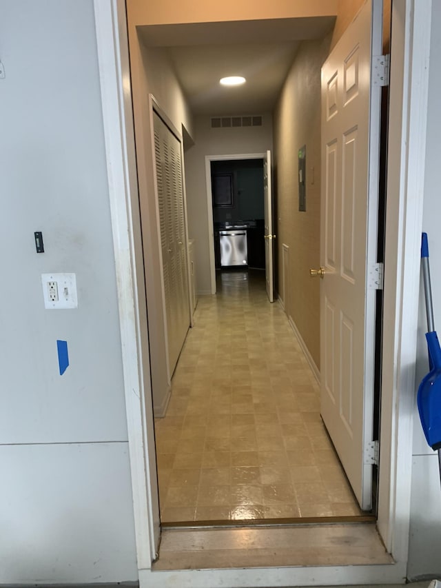 hallway with baseboards, visible vents, electric panel, and light floors