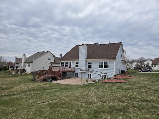 back of property featuring a deck, a chimney, roof with shingles, stairway, and a yard
