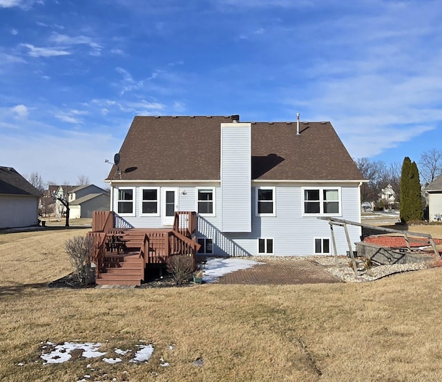 rear view of house with a shingled roof, a yard, and a chimney