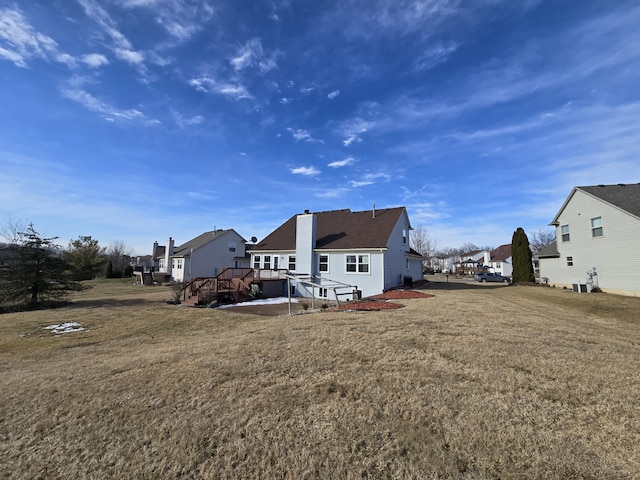 rear view of property with a wooden deck, cooling unit, a chimney, a lawn, and a residential view