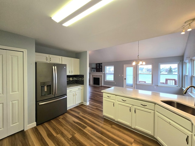kitchen with a sink, light countertops, dark wood finished floors, backsplash, and stainless steel refrigerator with ice dispenser