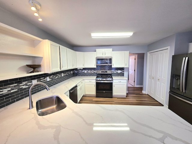 kitchen featuring decorative backsplash, stainless steel appliances, white cabinetry, and a sink