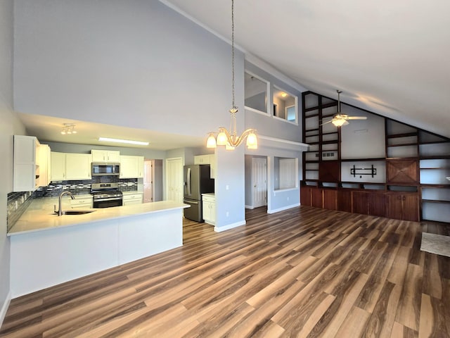 kitchen with decorative backsplash, a sink, high vaulted ceiling, open floor plan, and stainless steel appliances