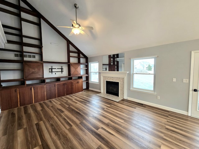 unfurnished living room featuring dark wood-style flooring, baseboards, a ceiling fan, vaulted ceiling, and a premium fireplace