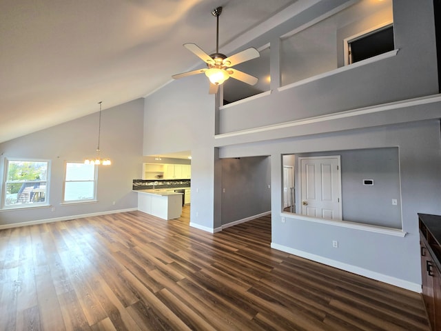 unfurnished living room with baseboards, dark wood finished floors, ceiling fan with notable chandelier, and high vaulted ceiling