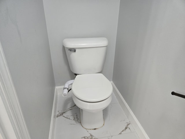 bathroom with toilet, baseboards, and marble finish floor