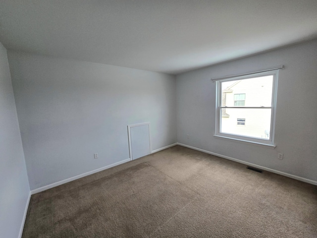 carpeted empty room featuring baseboards and visible vents