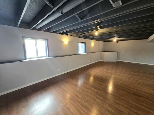 below grade area with baseboards, wood finished floors, and a healthy amount of sunlight