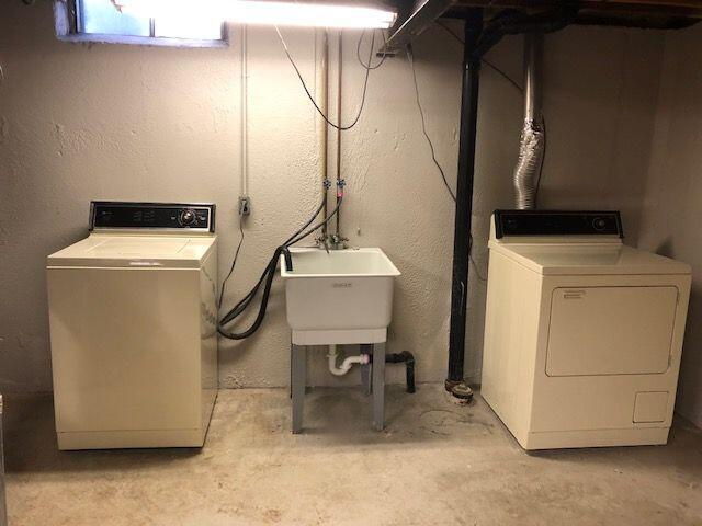 washroom with a sink, a textured wall, laundry area, and washing machine and clothes dryer