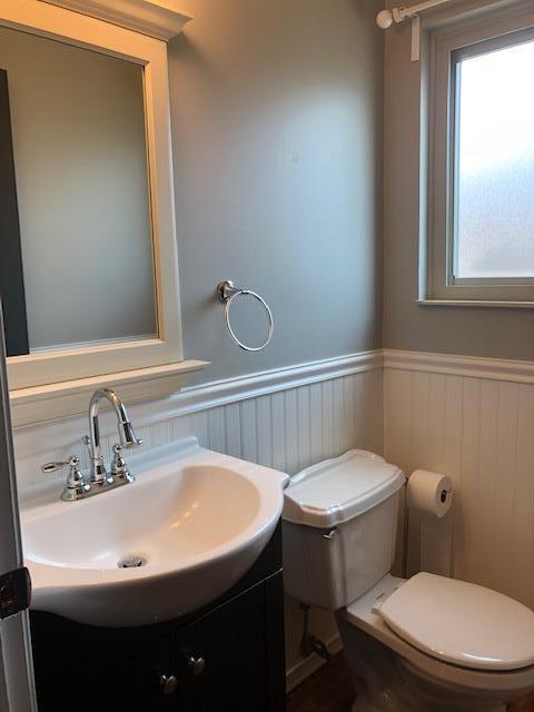 half bath featuring vanity, wainscoting, and toilet